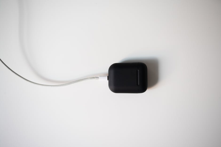 Illustration of an AirPods charging case with AirPods inside, showing the correct alignment and a white light indicator when charging.